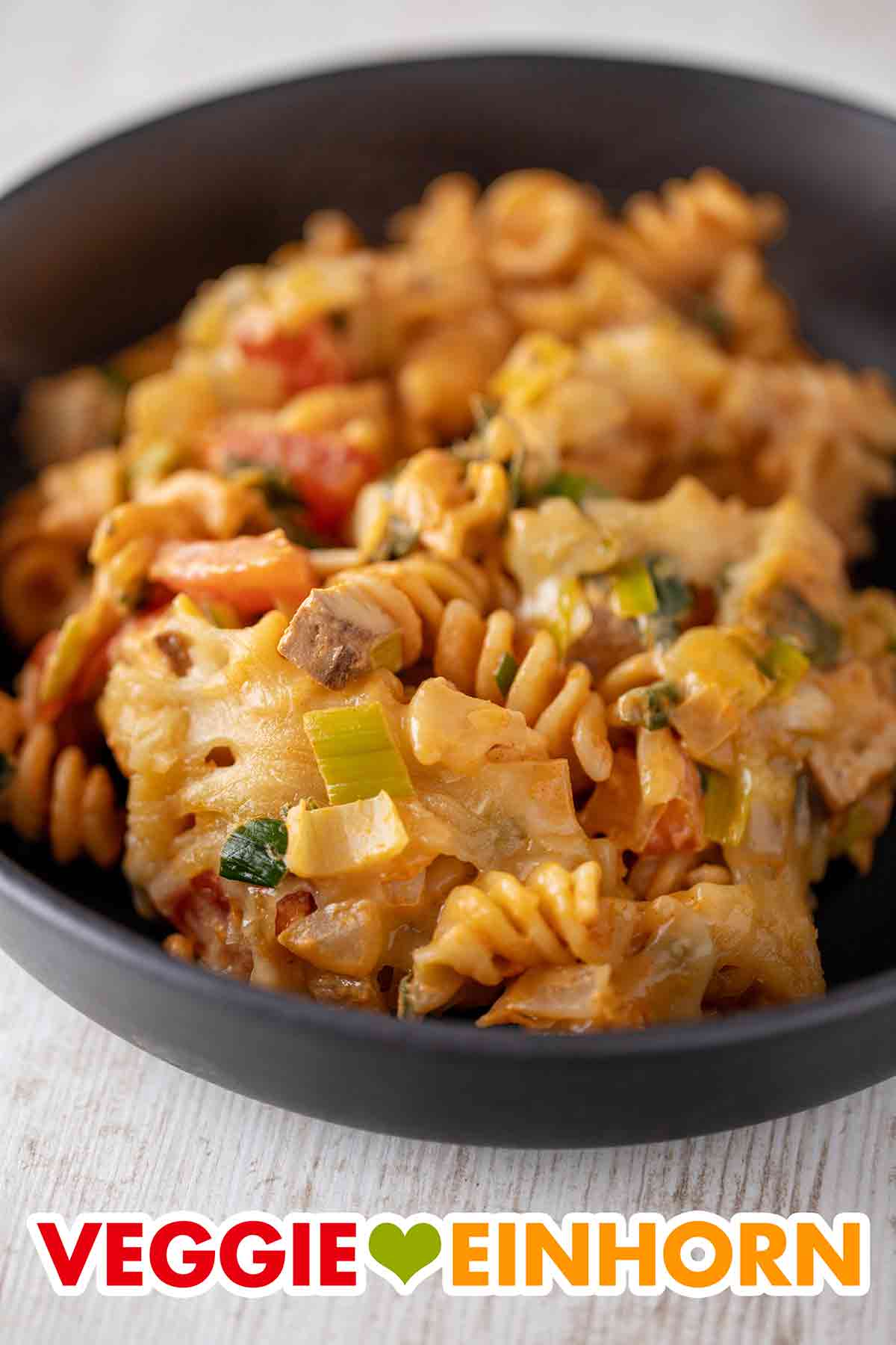 Hier sieht man gut die Räuchertofu Würfel und den veganen Reibekäse, mit dem der Auflauf überbacken ist. Veganer Nudelauflauf mit Räuchertofu, Lauch und Tomaten auf einem Teller