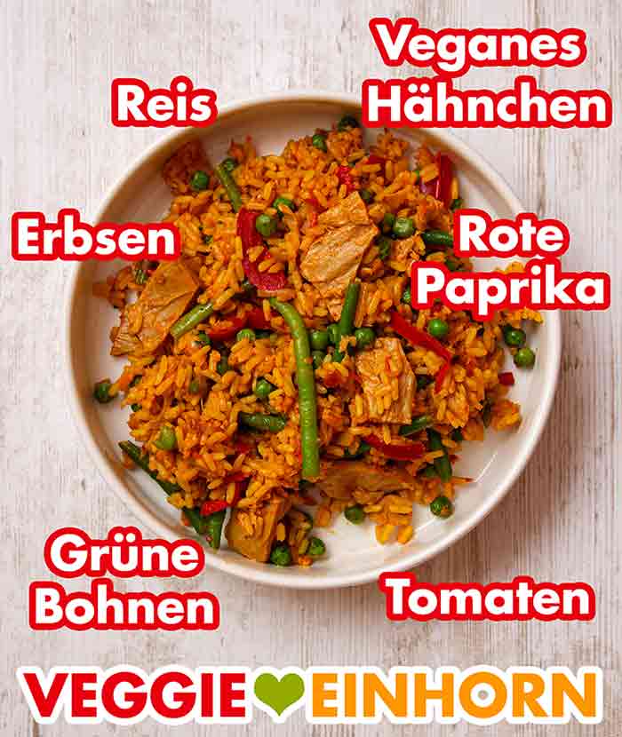 Die Veggie Hähnchen Paella von Frosta enthält veganes Hähnchen Fleisch, Reis, Erbsen, rote Paprika, grüne Bohnen und Tomaten. Die vegane Paella von Frosta auf einem Teller