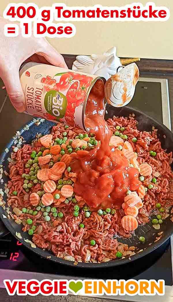 Eine 400 g Dose gehackte Tomaten zufügen. Eine Dose Tomatenstücke wird in die Pfanne hinzugefügt.