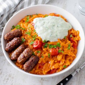 Tomaten Kritharaki mit veganem Tzatziki und veganen Cevapcici