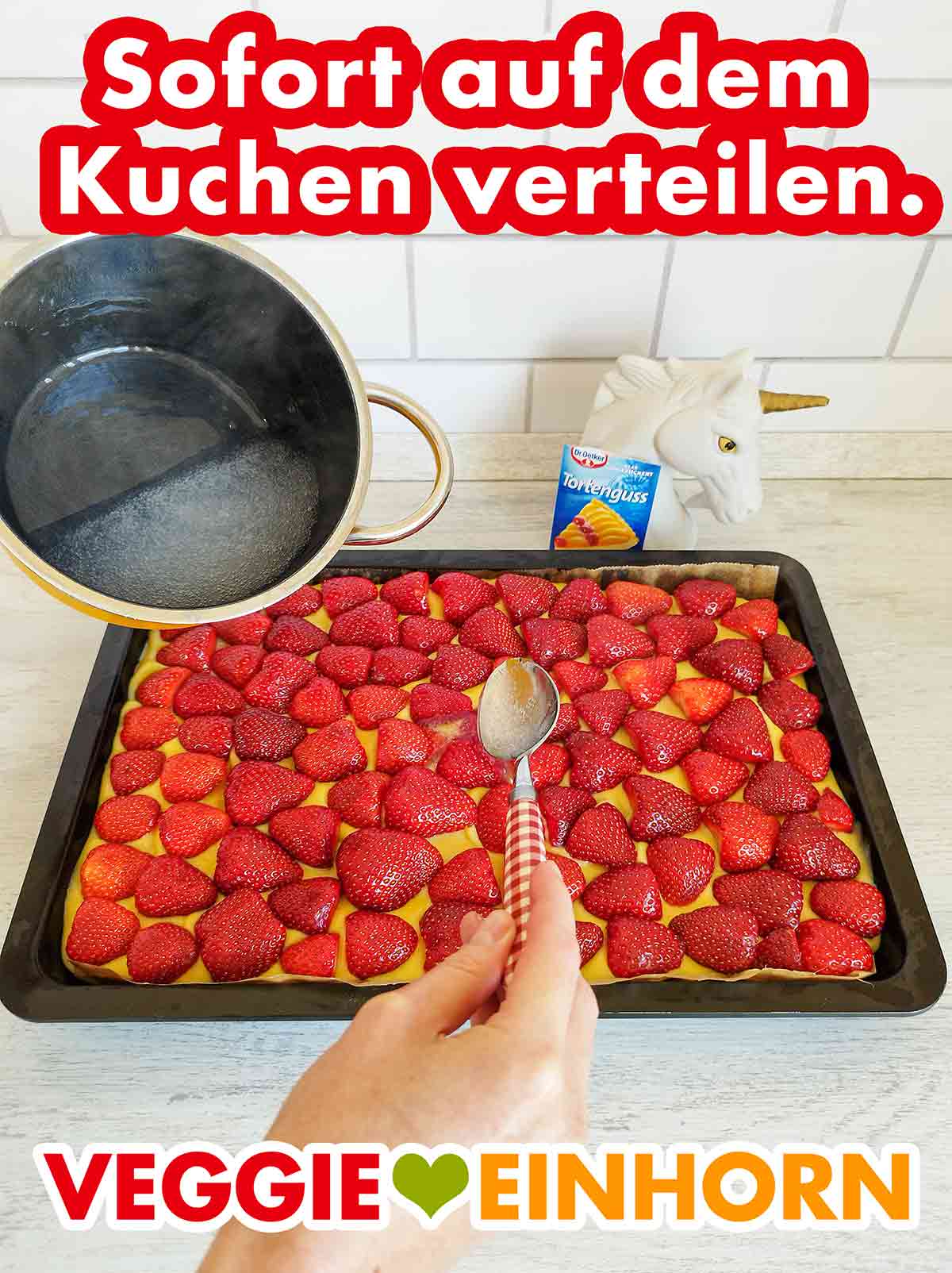 Den Tortenguss von der Mitte aus zügig verteilen. Der klare Tortenguss von Dr. Oetker wird auf einem veganen Erdbeerkuchen verteilt.