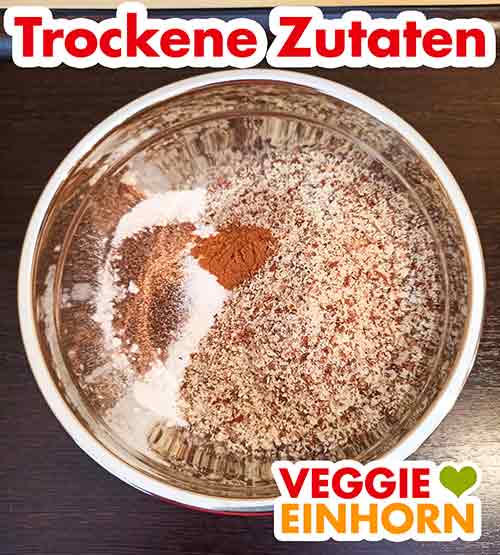 Die trockenen Zutaten für den Möhrenkuchen in einer Schüssel Mehl, gemahlene Mandeln, Zucker, Backpulver und Zimt in einer Rührschüssel