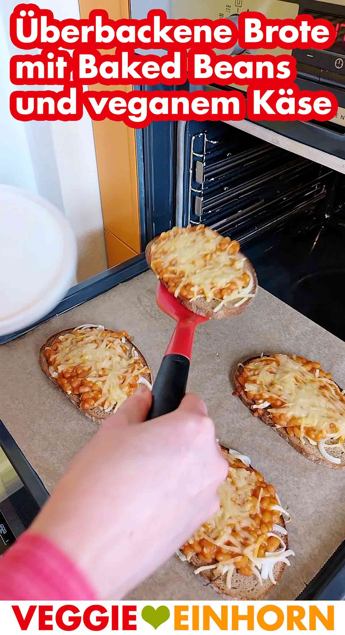 Die überbackenen Brotscheiben mit Baked Beans aus der Dose, Zwiebeln und beganem Käse sind fertig. Ein überbackenes Brot mit Baked Beans und veganem Reibekäse wird auf einen Teller gelegt.