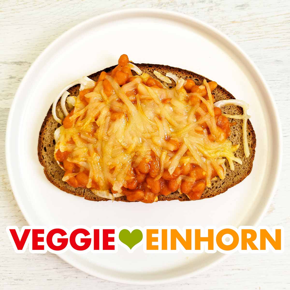 Das überbackene Brot ist vegetarisch und vegan. Überbackenes Brot mit veganem Käse, Baked Beans aus der Dose und Zwiebeln