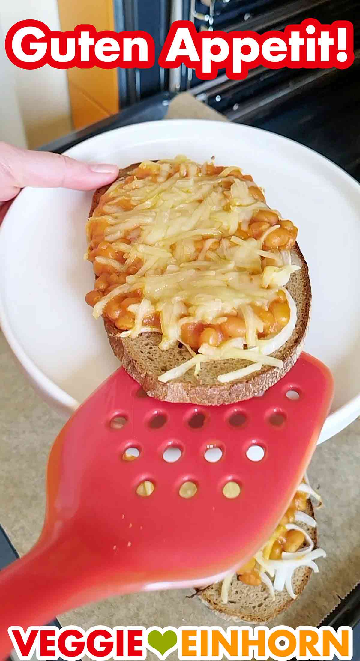 Die Graubrotscheibe ist mit Zwiebeln und Baked Beans aus der Dose belegt und mit veganem Reibekäse überbacken. Nahaufnahme von einem überbackenen Brot mit Baked Beans aus der Dose, Zwiebeln und veganem Käse