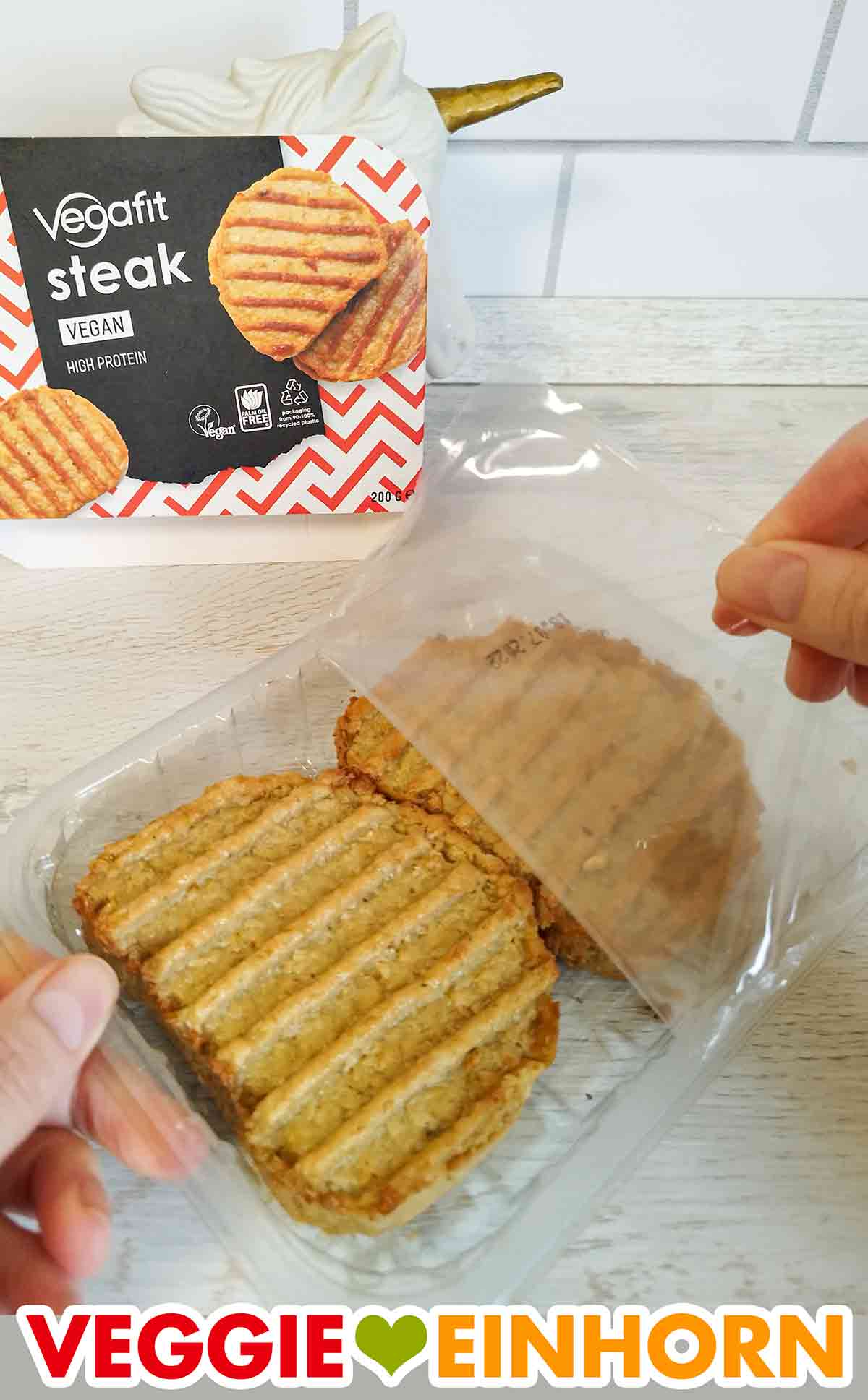 Die Deckelfolie wird von der Packung der veganen Steaks abgezogen. Abziehen der Folie von den Vegafit Steaks