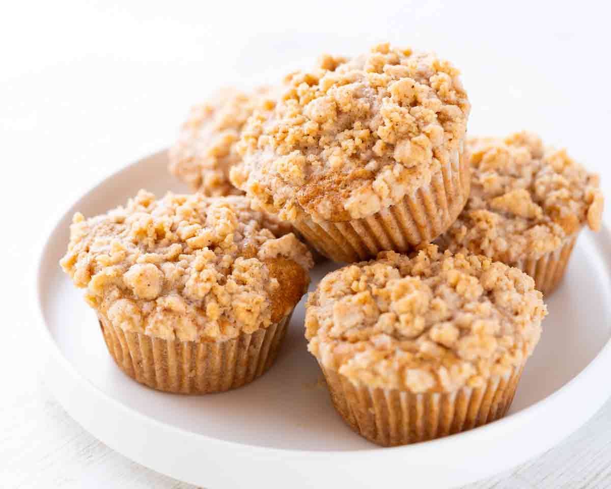 Vegane Apfel-Zimt-Muffins mit Streuseln auf einem weißen Teller.