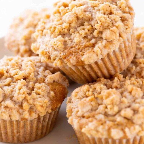 Mehrere vegane Apfel-Streusel-Muffins auf einem Teller in Nahaufnahme.
