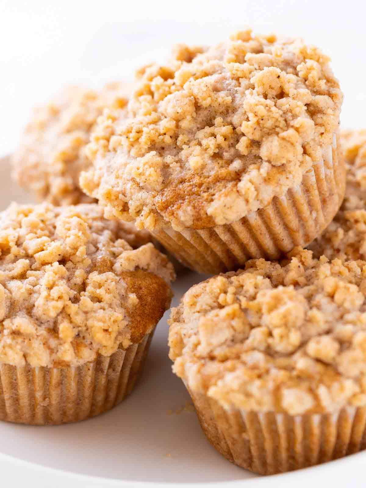 Mehrere vegane Apfel-Streusel-Muffins auf einem Teller in Nahaufnahme.