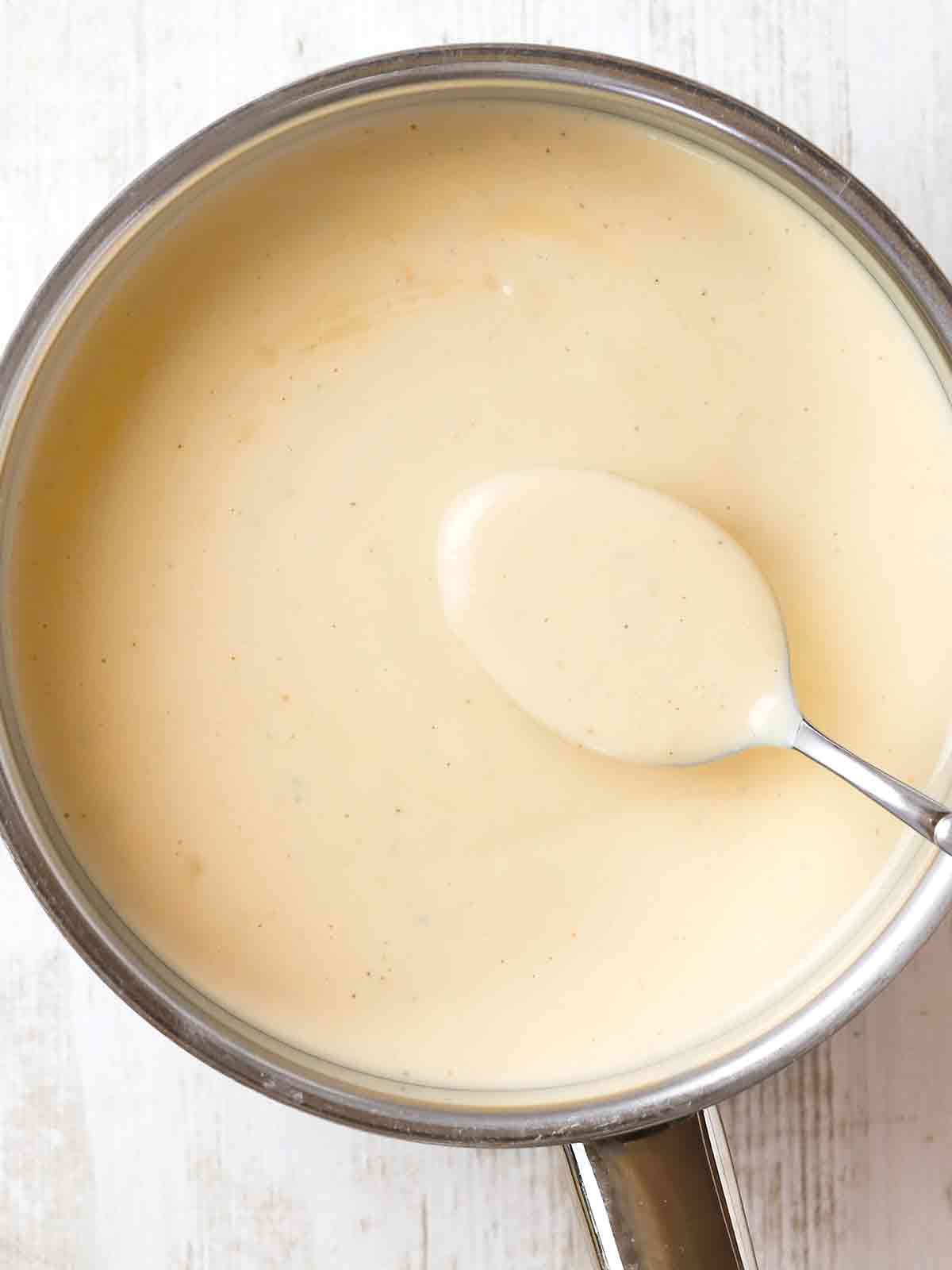 Vegane Béchamelsauce in einem Topf mit Löffel, von oben fotografiert