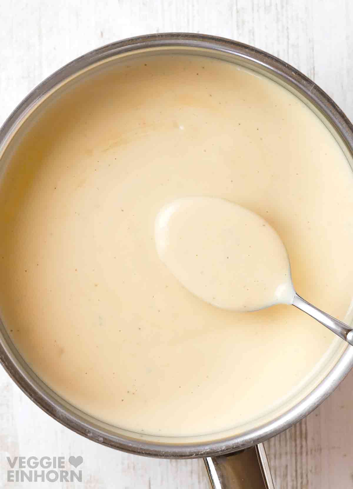 Vegane Béchamelsauce im Topf mit Löffel, Ansicht von oben.
