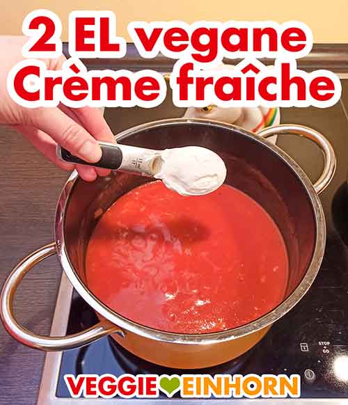 Zwei Esslöffel vegane Crème fraîche zur Tomatensuppe mit Reis geben Vegane Creme fraiche zufügen