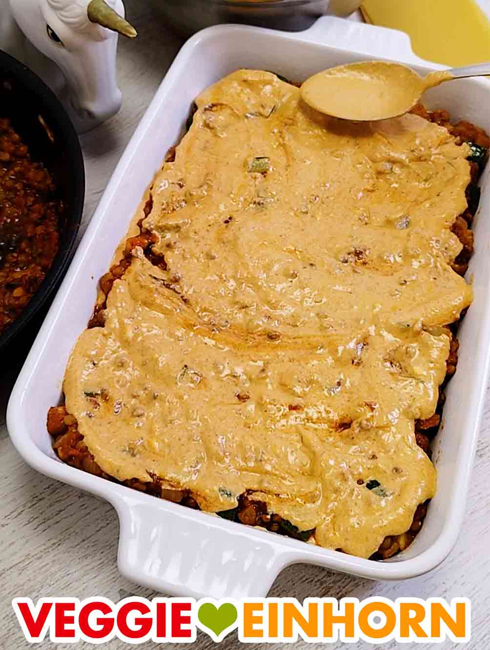 Die Soßen immer schön verteilen. Die vegane Frischkäsesoße wird mit einem Löffel verteilt.