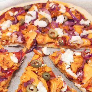 Vegane Gyrospizza mit roten Zwiebelringen, Oliven, veganem Gyros und zerbröseltem veganem Feta auf Tomatensoße.