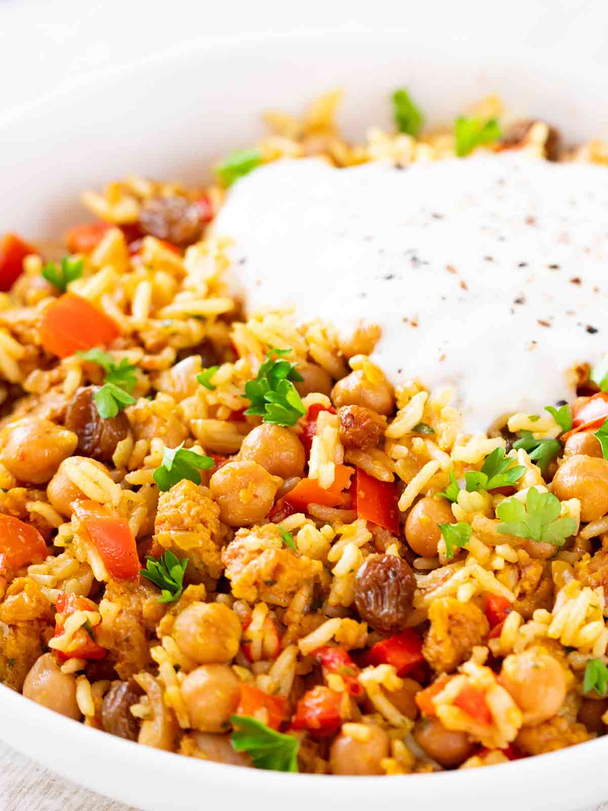 Nahaufnahme von veganer Hackfleisch-Reis-Pfanne mit Kichererbsen und veganer Joghurtsoße.