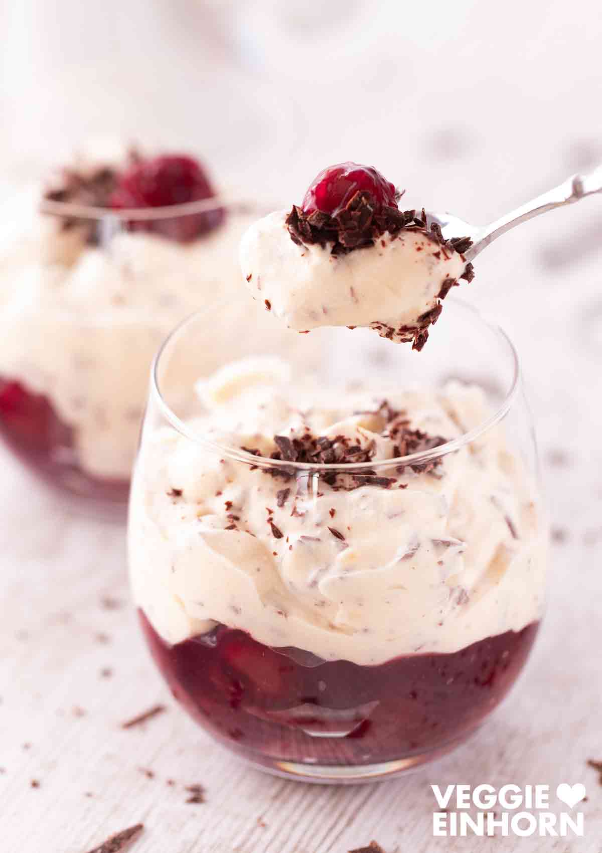 Die vegane Herrencreme mit Kirschen, Rum und Schokolade ist ein festlicher Nachtisch. Vegane Herrencreme mit Kirschen auf einem Dessertlöffel