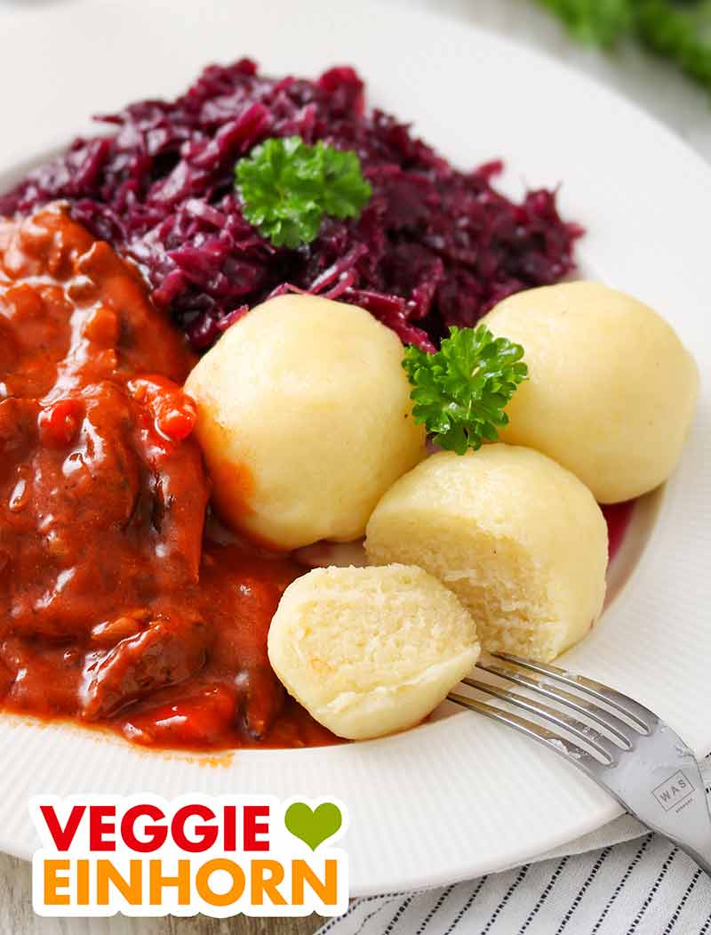 Vegane Kartoffelklöße mit veganem Gulasch und Rotkraut Ein Teller mit veganen Kartoffelknödeln, veganem Gulasch und Rotkohl
