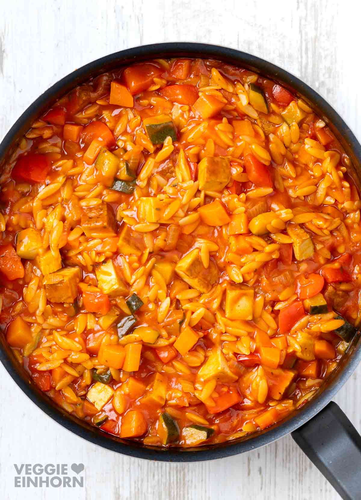 Vegane Kritharaki-Pfanne mit Räuchertofu und Gemüse in einer Pfanne.