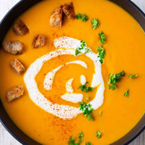 Teller mit veganer Kürbissuppe mit Kartoffeln und Karotten
