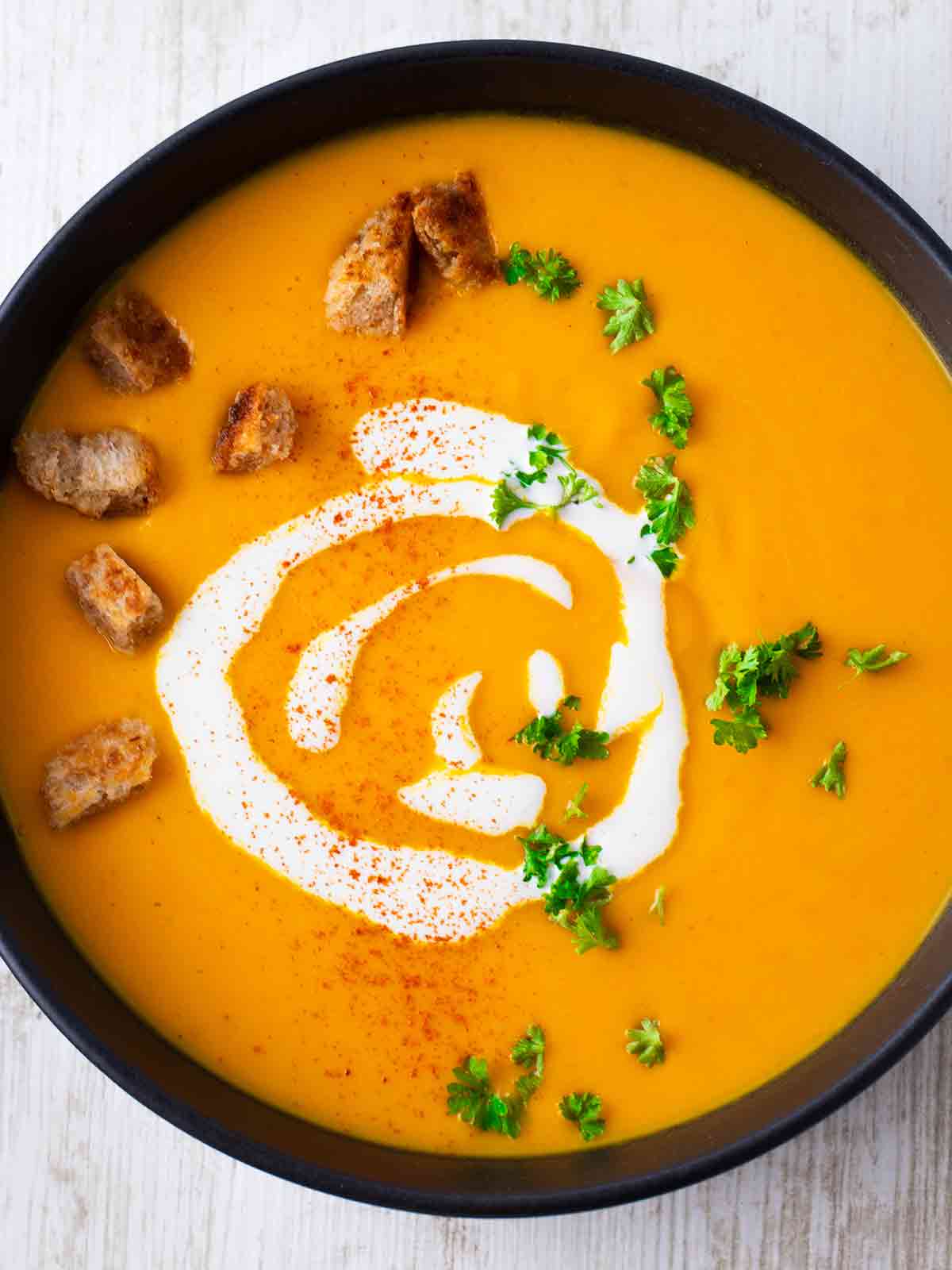 Teller mit veganer Kürbissuppe mit Kartoffeln und Karotten