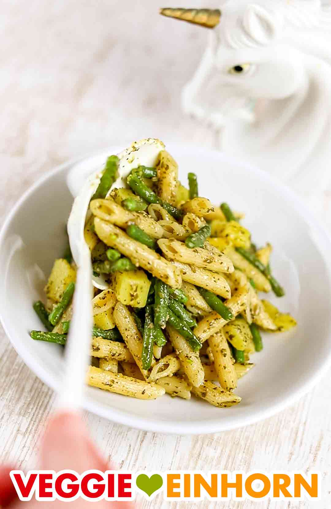 Die ligurische Pasta mit Bohnen und Kartoffeln wird serviert. Ligurische Nudeln mit grünen Bohnen und Kartoffeln werden auf einen Teller gegeben.