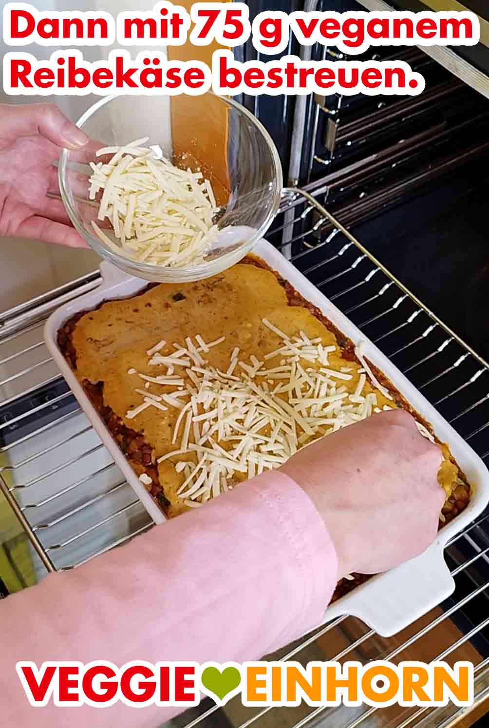 Nach den ersten 25 Minuten Backzeit wird die Linsenlasagne mit veganem Reibekäse bestreut. Bestreuen der Linsenlasagne mit veganem geriebenen Käse