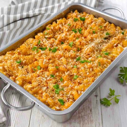 Vegane Mac and Cheese, goldbraun gebacken, mit Röstzwiebeln bestreut und in einer Metallform serviert.