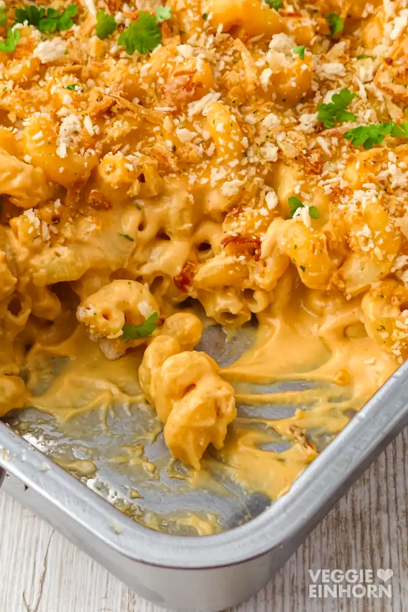 Detailaufnahme von cremigen veganen Mac and Cheese mit veganer Käsesoße, Röstzwiebeln, Panko  und Petersilie.