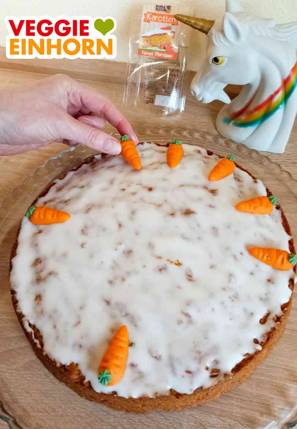 Der Karottenkuchen wird mit veganen Marzipanmöhren verziert. Vegane Marzipan Karotten werden auf den feuchten Zuckerguss gelegt