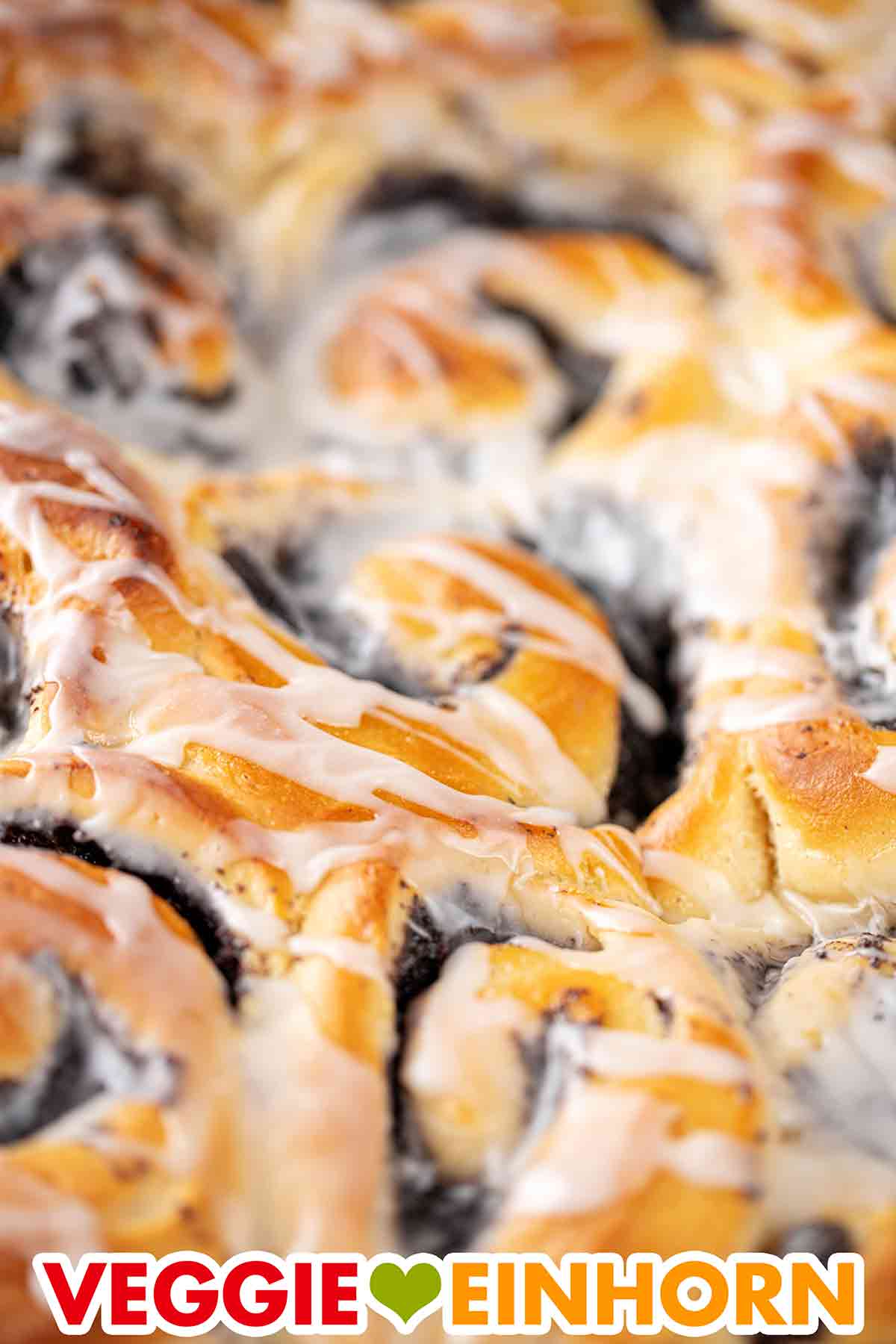 Der Zuckerguss für die Mohnschnecken ist aus Puderzucker und veganer Milch. Nahaufnahme von veganen Mohnschnecken mit Mohnfüllung und Glasur