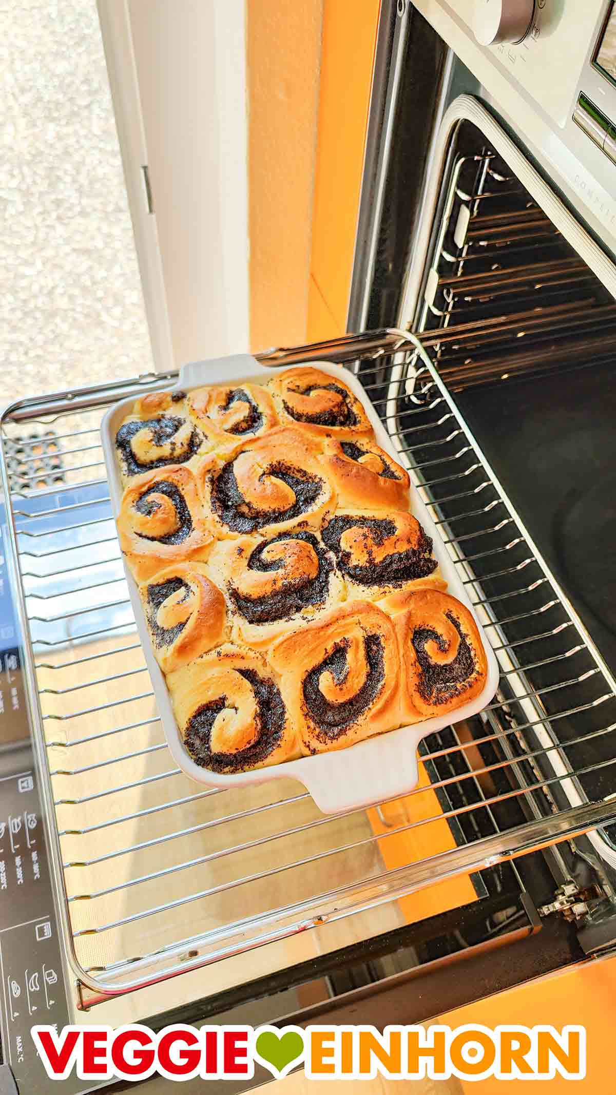 Die frisch gebackenen Mohnschnecken kühlen ab. Fertig gebackene vegane Mohnschnecken vor dem geöffneten Backofen