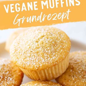 Mehrere goldbraune vegane Muffins in Papierförmchen, mit Puderzucker bestäubt. Oben im Bild ein angebissener Muffin. In der Mitte steht der Text Vegane Muffins Grundrezept.