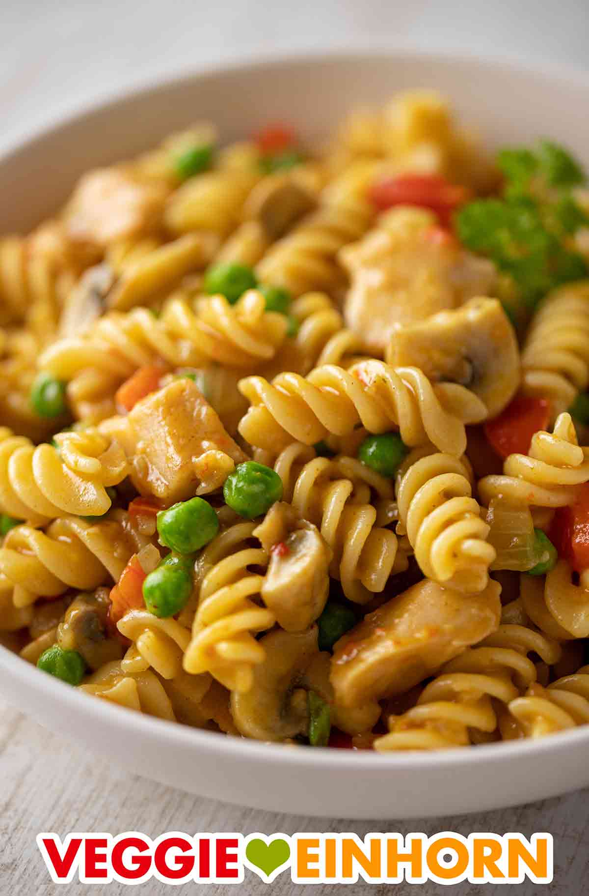 Die Nudelpfanne enthält veganes Hähnchen, Paprika, Pilze und Erbsen. Nahaufnahme von Nudelpfanne mit Gemüse und veganem Hähnchenfleisch