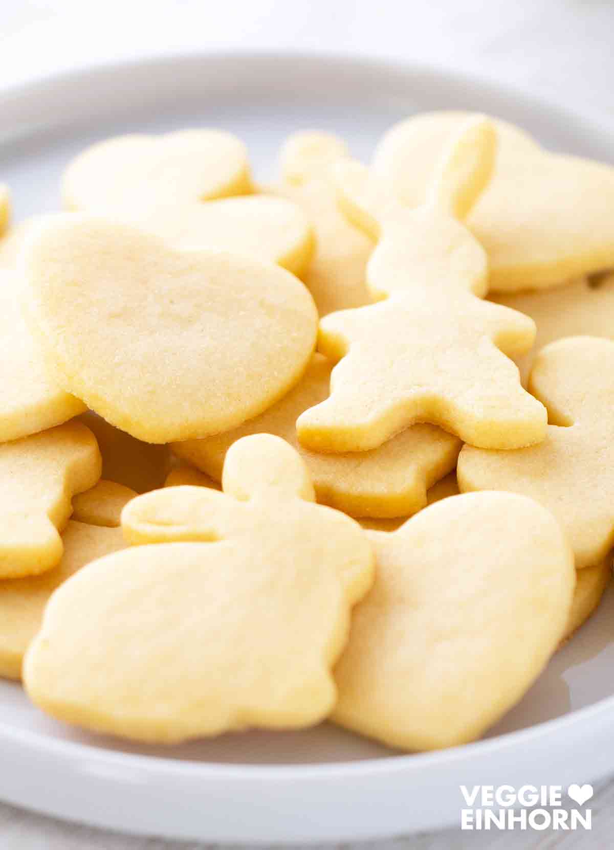Vegane Osterplätzchen in Hasenform und Herzform auf einem weißen Teller.