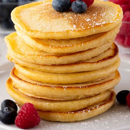 Ein Stapel vegane Pancakes mit Beeren und Puderzucker