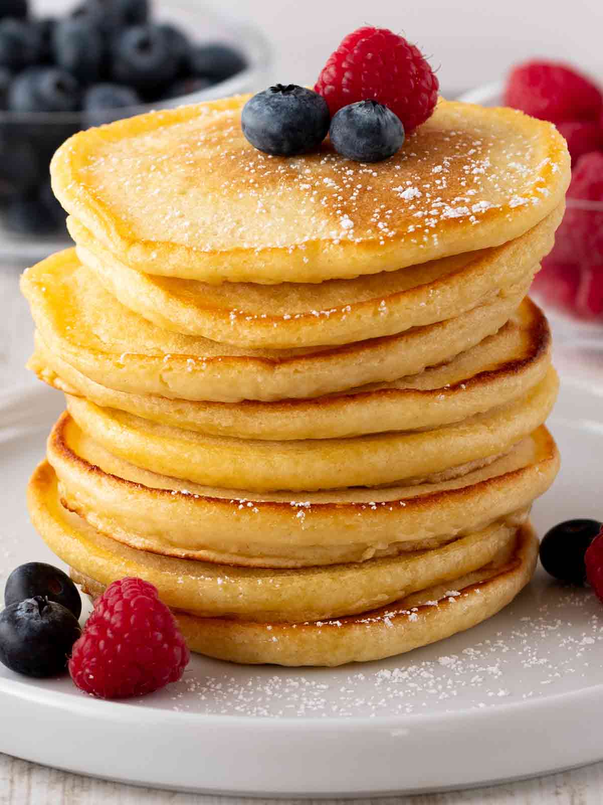 Ein Stapel vegane Pancakes mit Beeren und Puderzucker