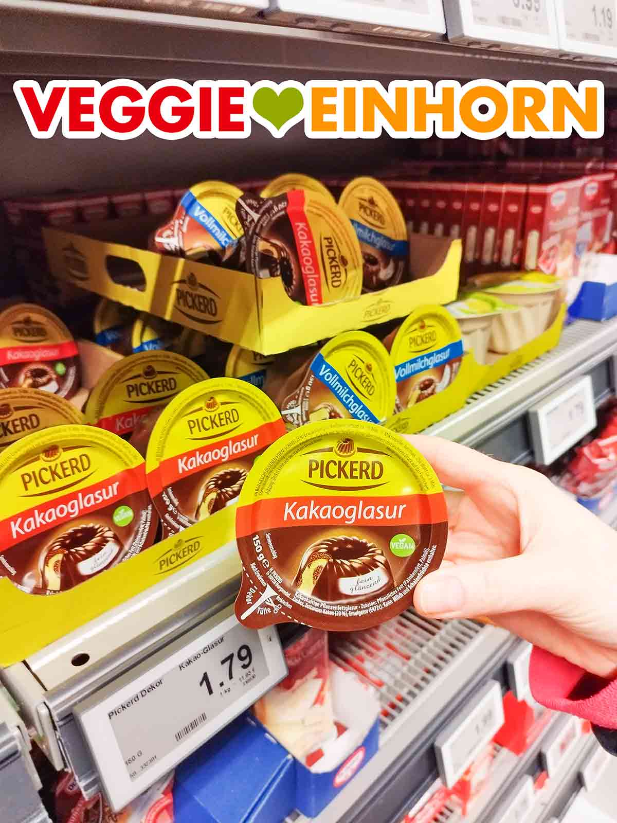 Die Kakaoglasur von Pickerd ist eine sehr beliebte vegane Schokoglasur. Eine Hand hält eine Packung vegane Pickerd Kakaoglasur im Supermarkt