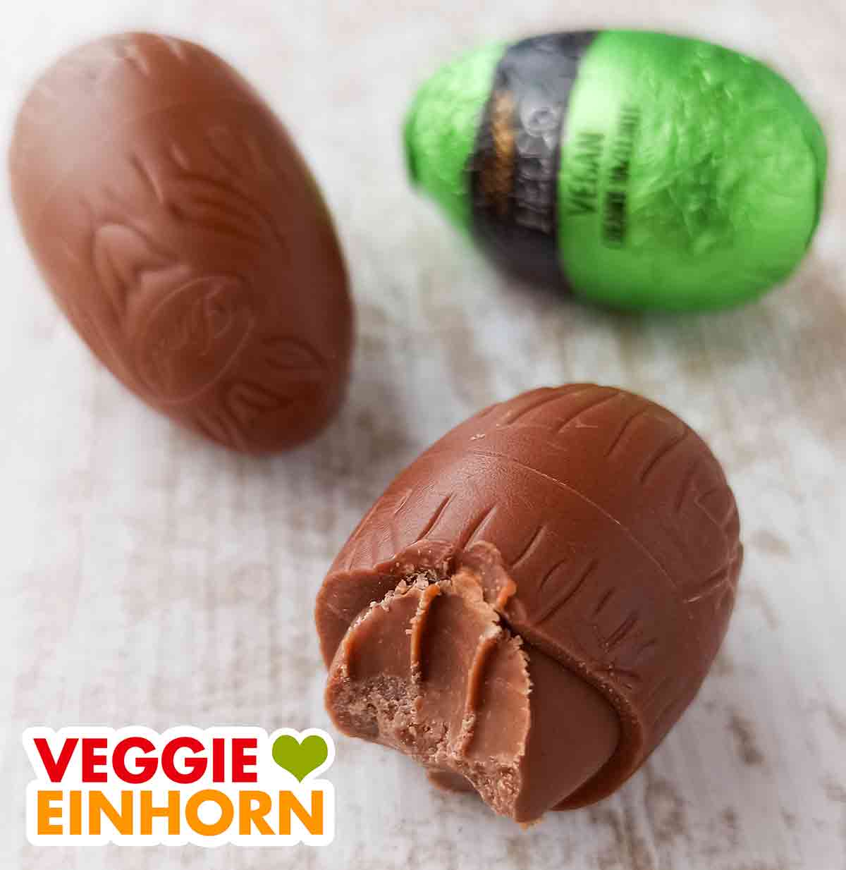 Die Füllung ist zart schmelzend und cremig. Die Konsistenz ist wie Nougat. Angebissenes veganes Schokoei mit Haselnuss Creme Füllung
