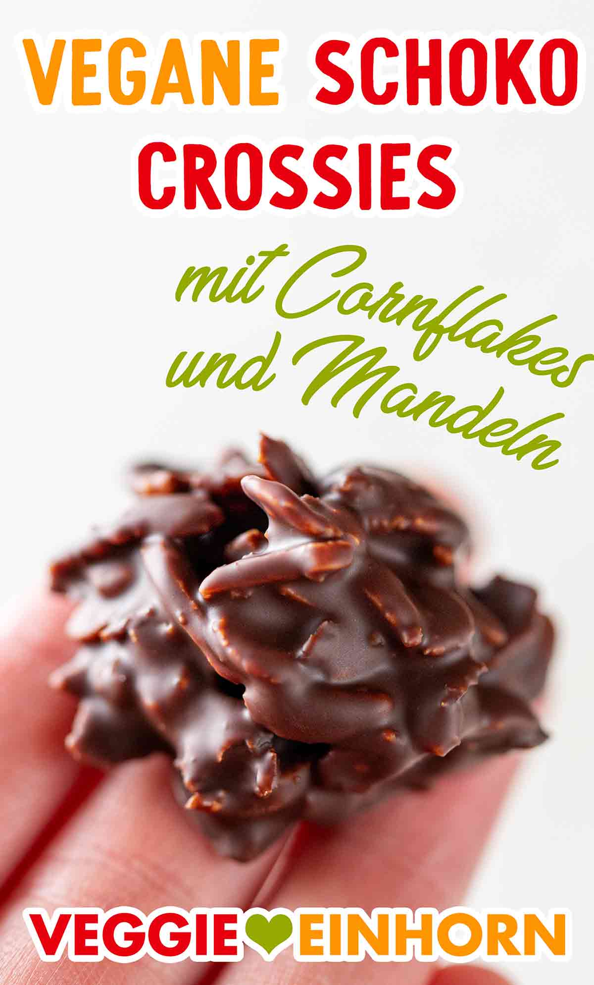 Die veganen Schokocrossies sind aus Cornflakes, veganer Schokolade, Mandelstiften und Kokosfett. Eine Hand hält einen veganen Schoko Crossie