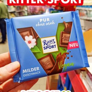 Eine Hand hält eine Tafel Ritter Sport Pur ohne muh im Supermarkt