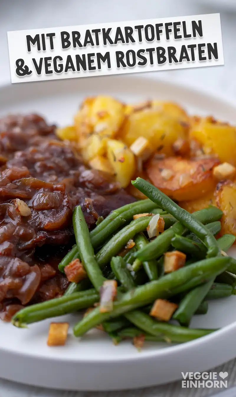 Vegane Speckbohnen als Beilage auf einem Teller, serviert mit Bratkartoffeln und veganem Rostbraten in dunkler Soße.