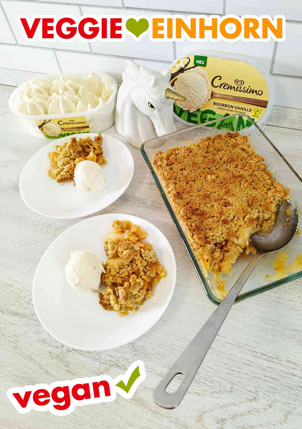 Der Apple Crumble und das vegane Vanilleeis Eine Packung veganes Cremissimo Eis, zwei Dessertteller und eine Auflaufform mit veganem Apfel Crumble