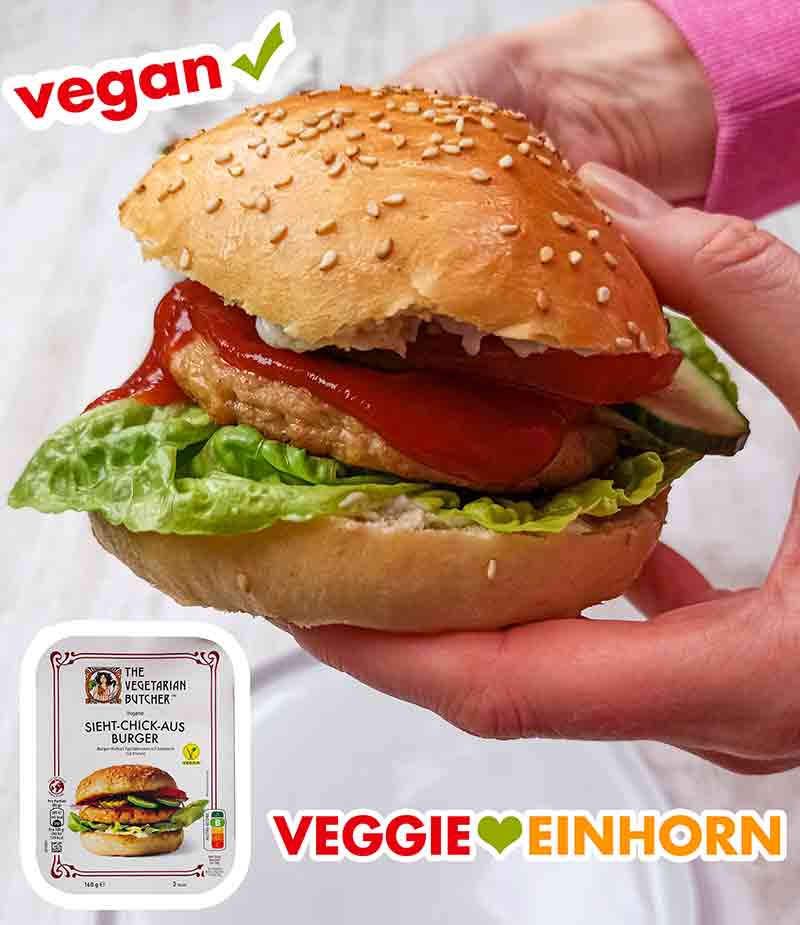 Die veganen Burgerbrötchen sind selbst gebacken, und der Patty ist der vegane Sieht-Chick-Aus Burger von The Vegetarian Butcher. Zwei Hände halten einen veganen Chicken Burger mit Patty von The Vegetarian Butcher