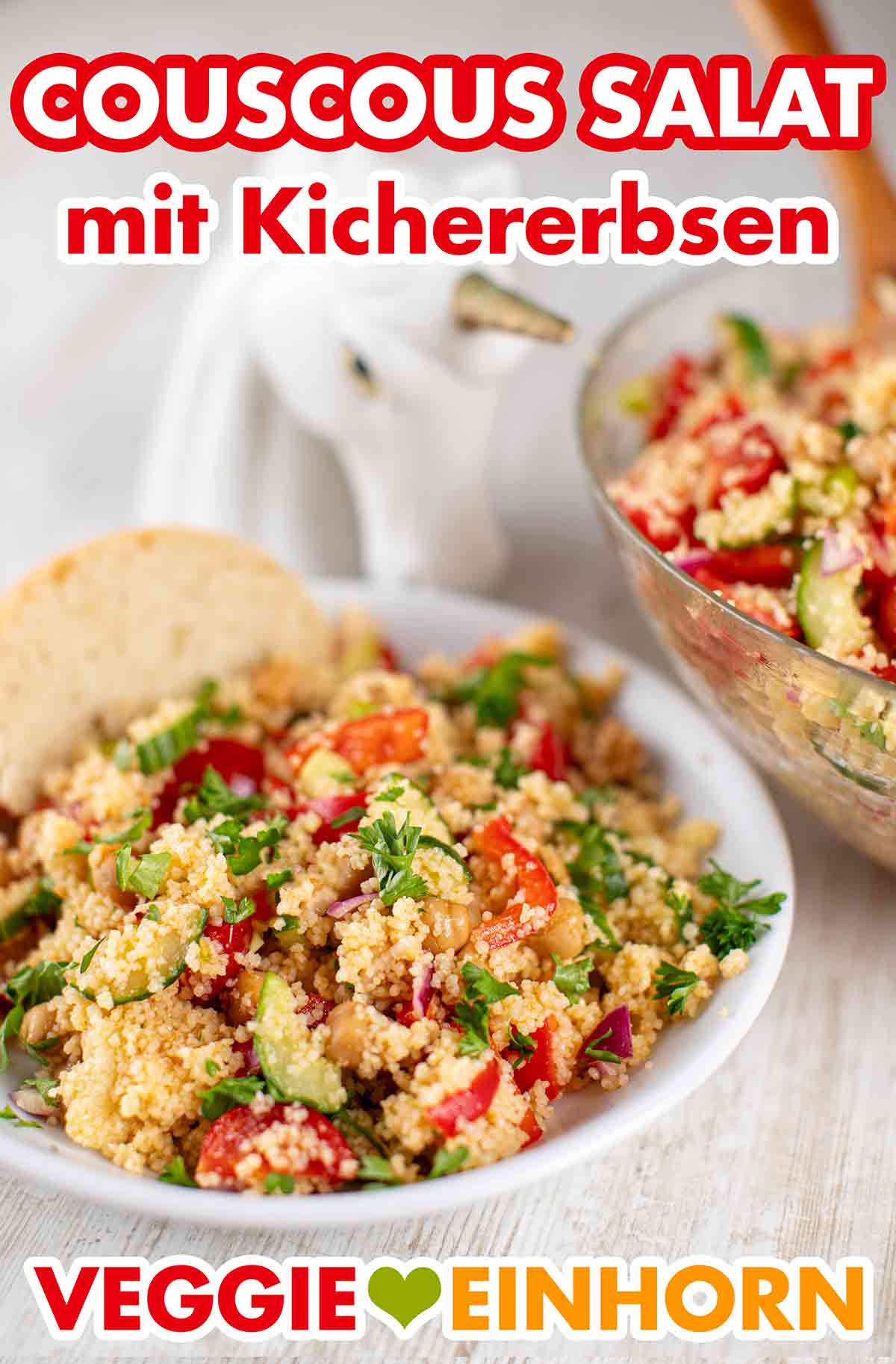 Der sommerliche Couscous Salat enthält Kichererbsen, Salatgurke, Paprika und Kirschtomaten. Ein Teller mit Couscoussalat und einer Scheibe Baguette