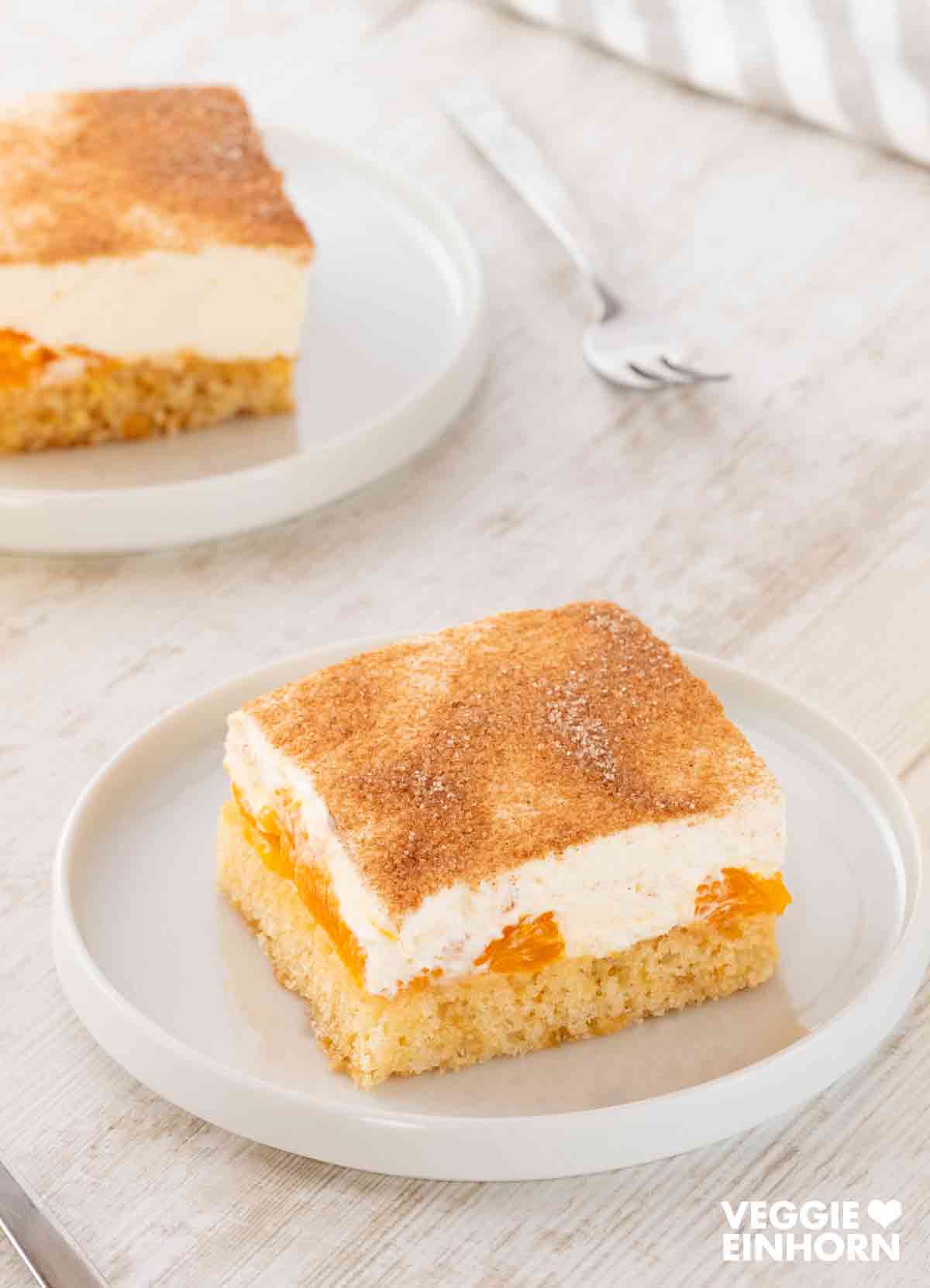 Zwei Stücke veganer Mandarinen-Schmand-Kuchen Zwei Teller mit veganem Fantakuchen mit Schmand und Mandarinen