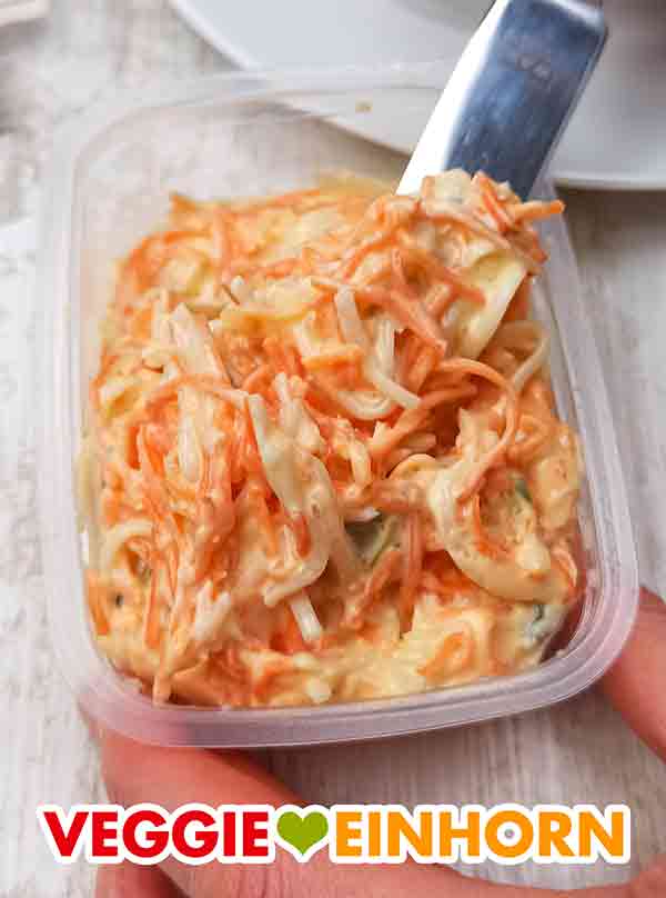 Der vegane Farmersalat von Popp enthält Karotten, Sellerie, Porree und vegane Salatmayonnaise. Geöffnete Packung Popp Veganer Farmersalat mit einem Messer