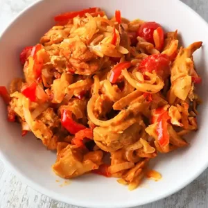 Eine Portion veganer Gyrosauflauf mit Kritharaki, Paprika, Zwiebeln und Tomaten auf einem weißen Teller.
