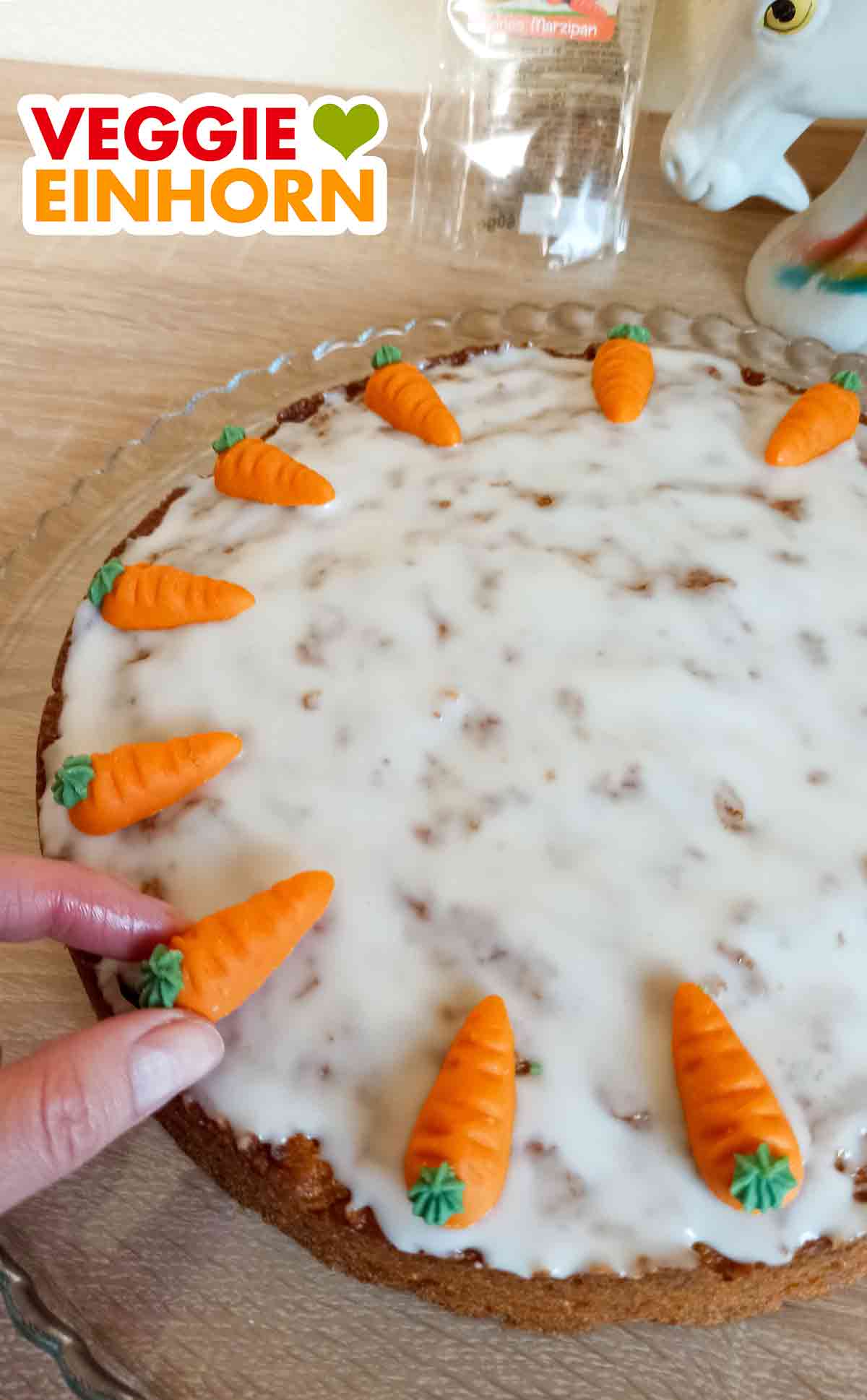 Die veganen Marzipankarotten werden auf einen veganen Rüblikuchen gelegt. Dekorieren eines veganen Karottenkuchens mit veganen Marzipankarotten