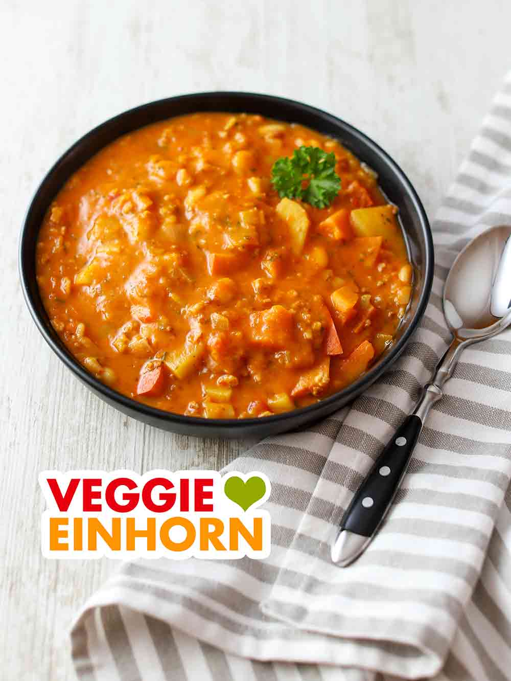 Herzhafter veganer Eintopf mit Hokkaido und Sojagranulat Ein Teller veganer Kürbiseintopf mit Kartoffeln