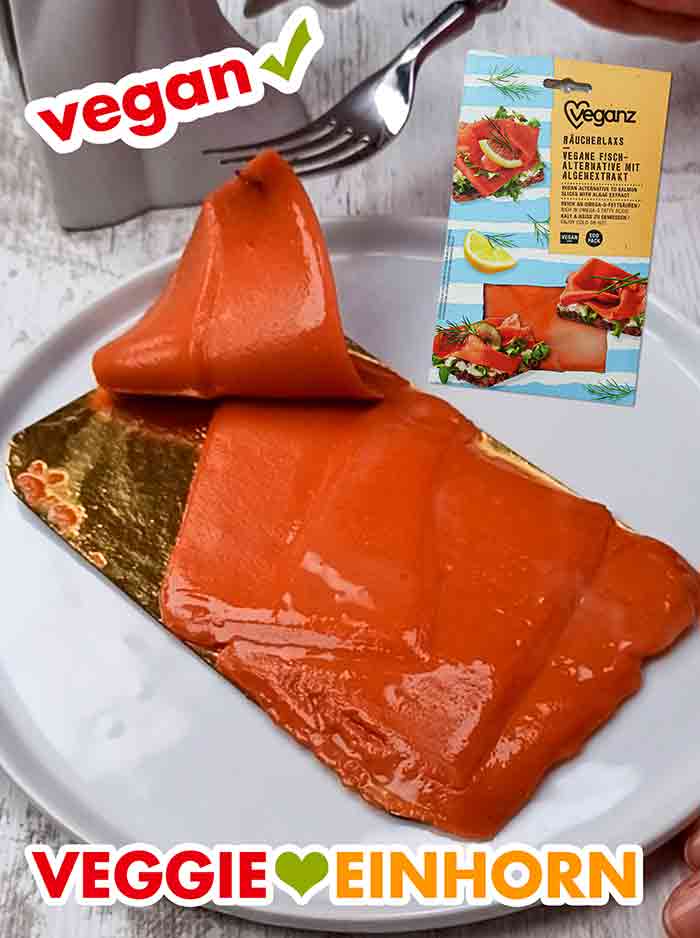 In der Packung sind 4 Scheiben veganer Lachs (100 g). Eine Scheibe Veganz Räucherlachs wird mit einer Gabel angehoben.